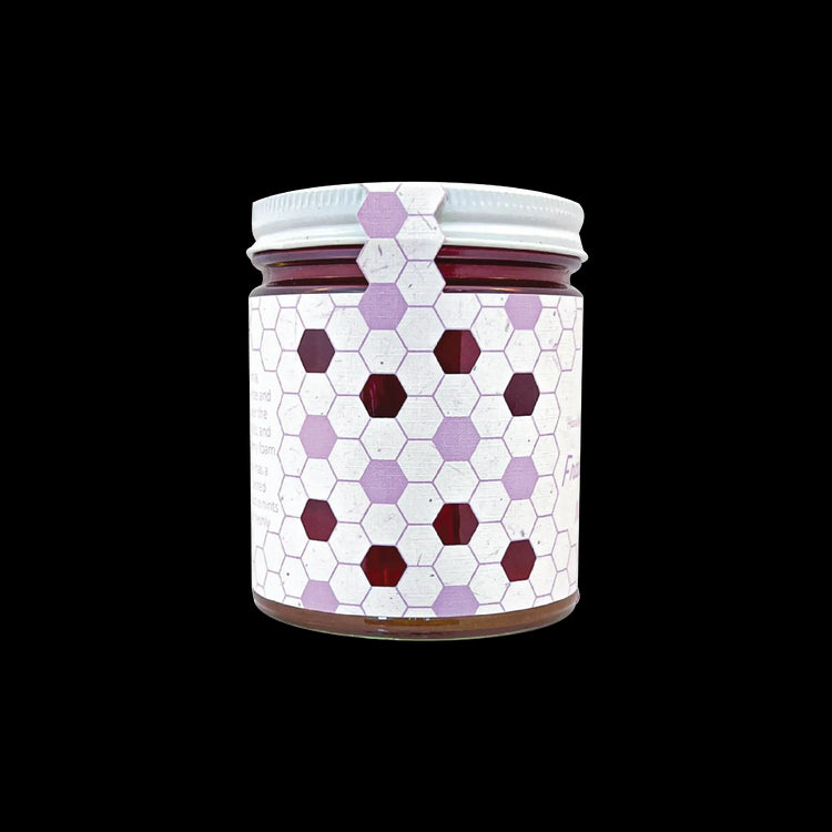 Northwestern Meadowfoam Honey in glass jar with purple and burgundy hexagonal pattern design on white label