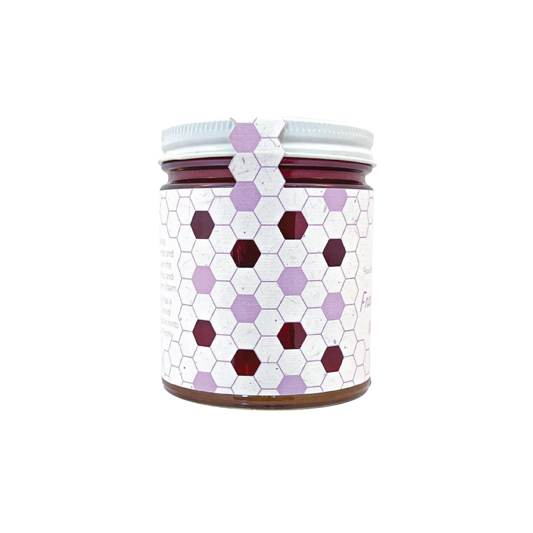 Northwestern Meadowfoam Honey in glass jar with purple and burgundy hexagonal pattern design on white label