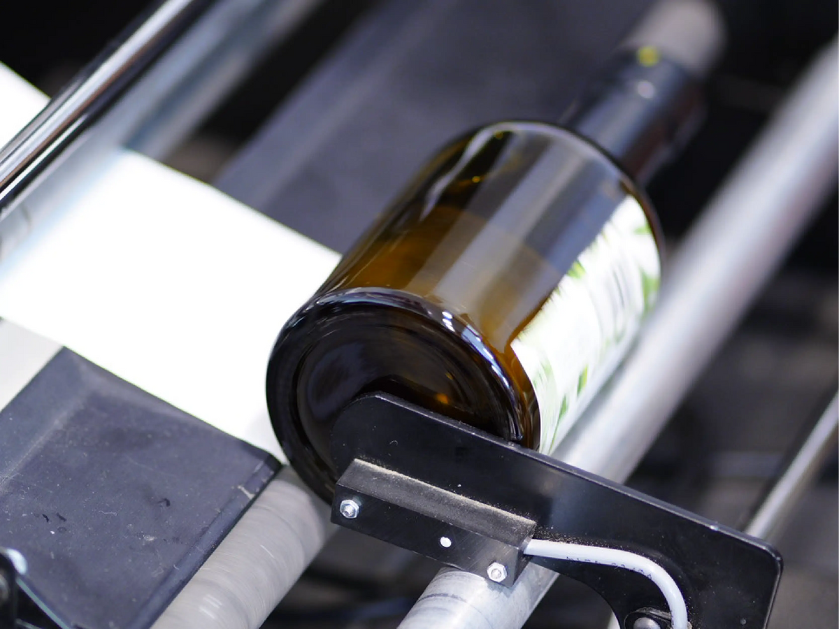 A bottle of olive oil passing through the labeling machine