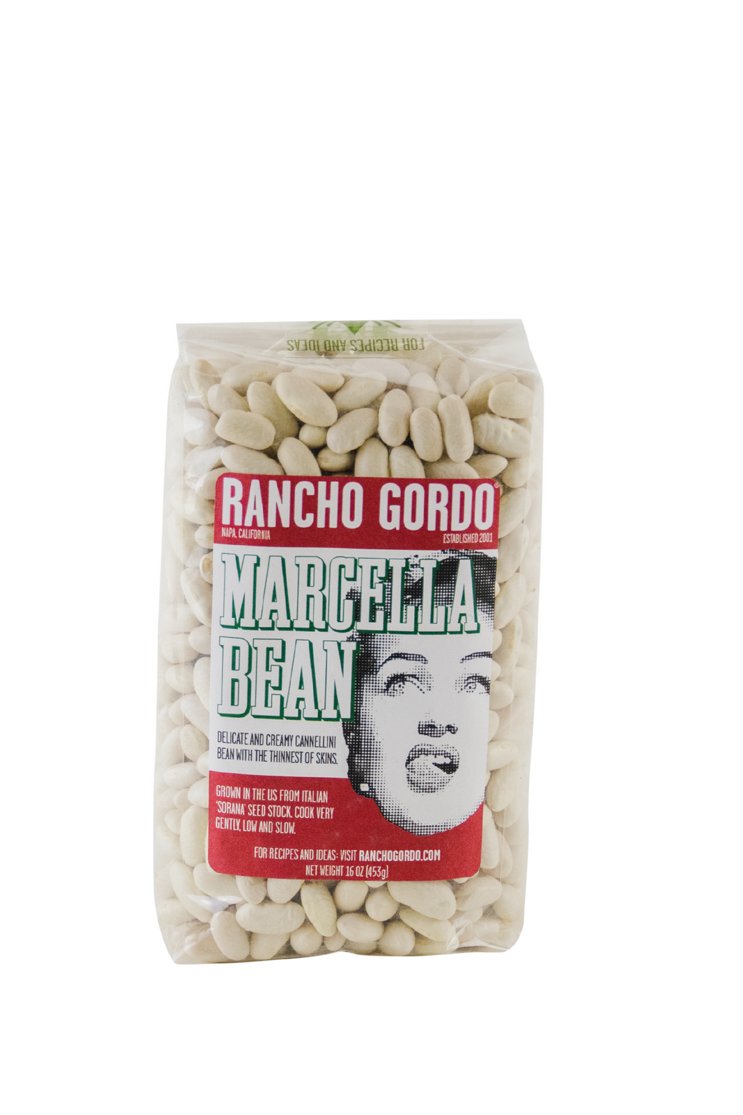 A One Pound Bag Of Rancho Gordo Marcella beans on a white background. Red and white label with an image of the face of a woman licking her upper lip. Additional text on bag reads: Delicate and creamy cannellini bean with the thinnest of skins. Grown in the US from Italian 'Sorana' seed stock, cook very gently, low and slow.