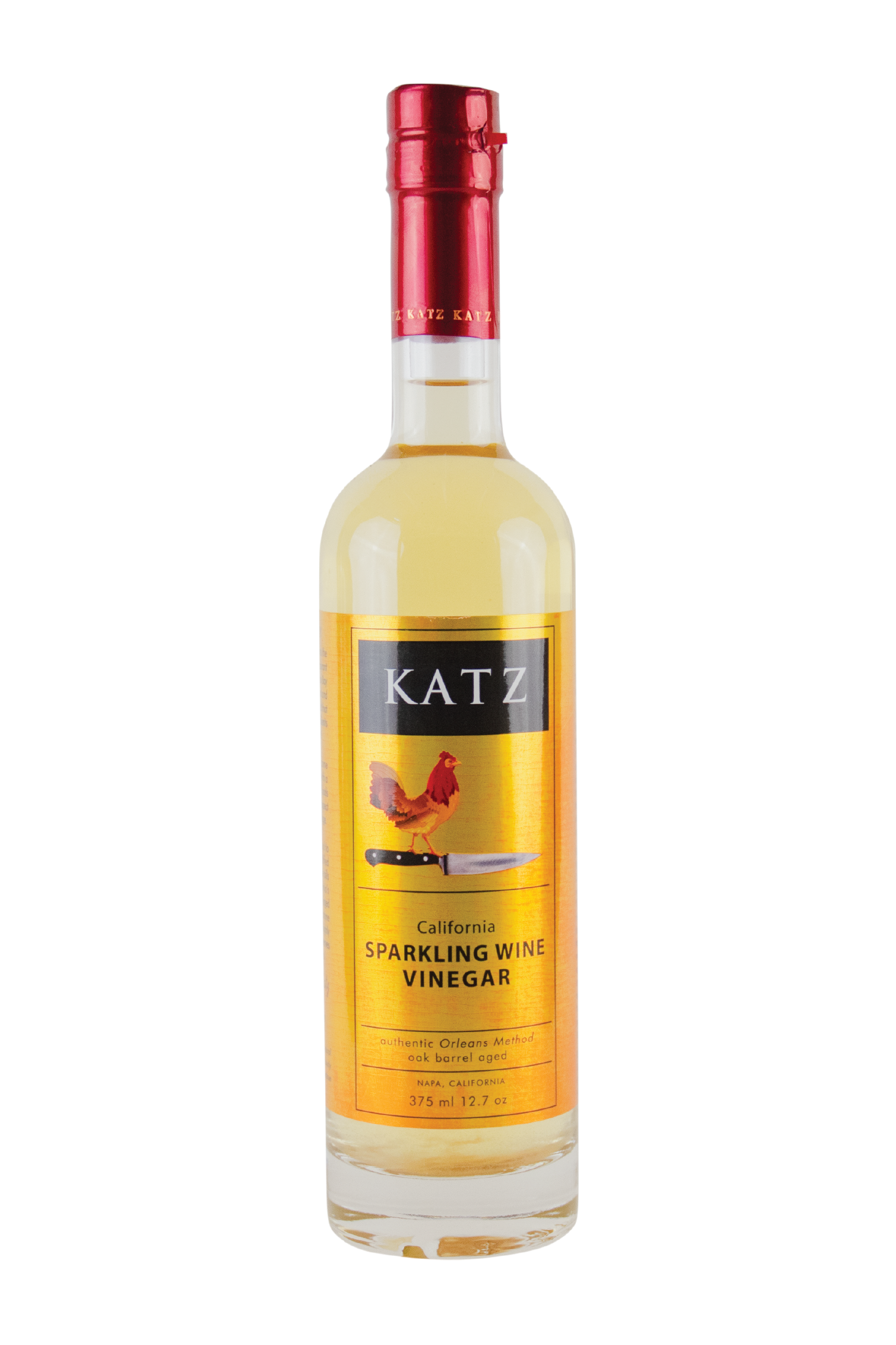 A 375 ml/12.7 oz glass bottle of Katz Sparkling Wine Vinegar on a white background. Label is gold and black with the image of a rooster standing on the hilt of a chef's knife and the words, "Authentic Orleans Method, oak barrel aged" and "Napa, California" on the bottle. Vinegar is a pale yellow, visible through the clear glass bottle with red foil shrink wrap on the top with the word "Katz" printed around the circumference.