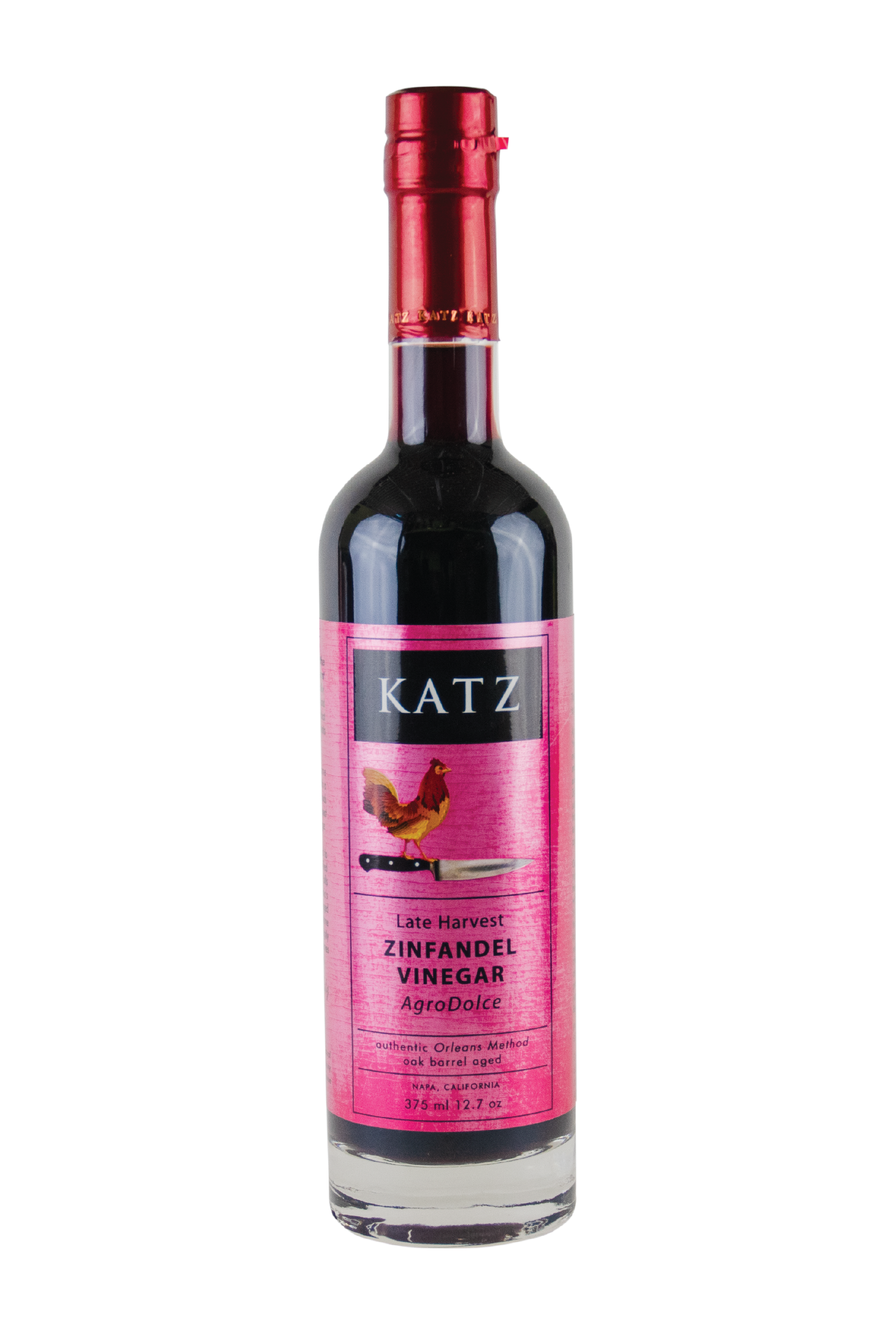 A 375 ml/12.7 oz glass bottle of Katz Late Harvest Zinfandel Agrodolce Vinegar on a white background. Label is light red green and black with the image of a rooster standing on the hilt of a chef's knife and the words, "Authentic Orleans Method, oak barrel aged" and "Napa, California" on the bottle. Vinegar is a dark burgundy, visible through the clear glass bottle, with red foil shrink wrap on the top with the word "Katz" printed around the circumference.