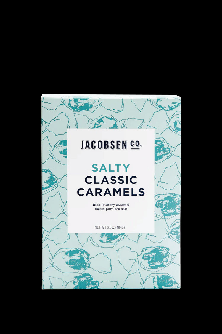 A Photo of Jacobsen Salt Co's Salty Classic Caramels in a pale blue box with stylistic renderings of caramels in wax paper wrappers in teal. Box says "Rich, buttery caramel meets pure sea salt." White background.