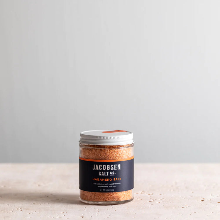 A Jar of Jacobsen Salt Co's Habanero Salt with a blue label on a stone surface 