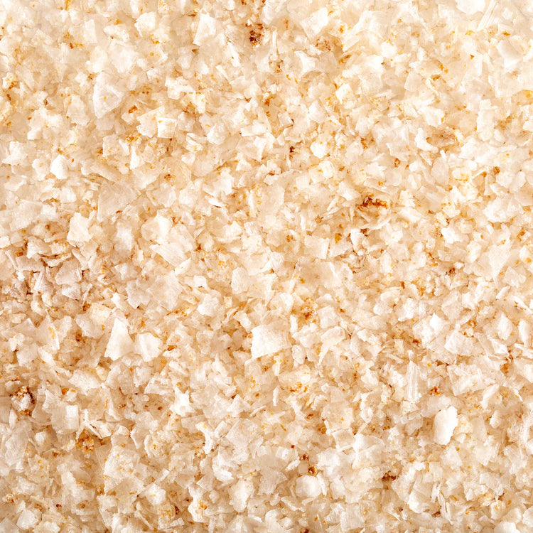 A Closeup of Lemon Zest Salt, showing the large, flaked texture and pale yellow color mixed with flecks of darker salt crystals.